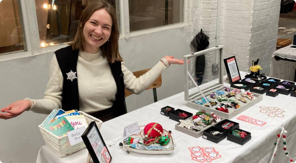 Olya smiling at her brooch table at a market